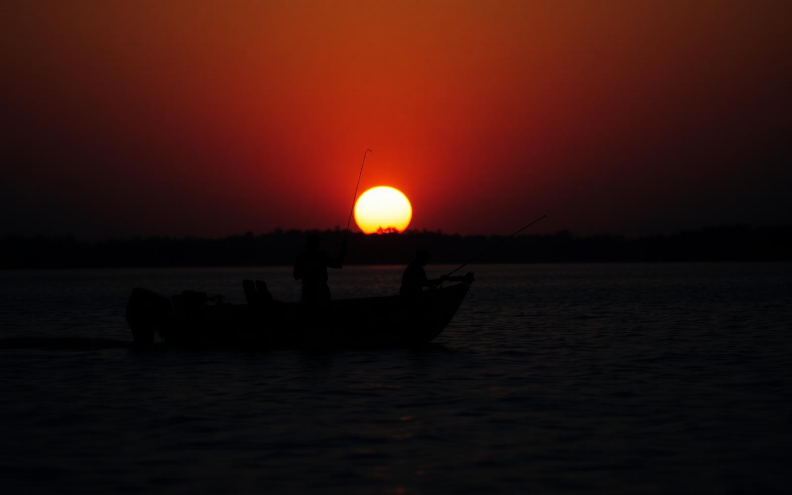 Anglers on a bass boat at sunset on an Austin lake